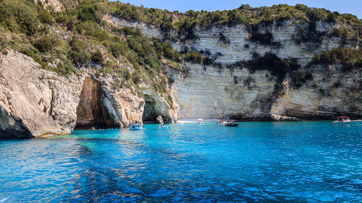Rocky cliffs with boats on vibrant blue water