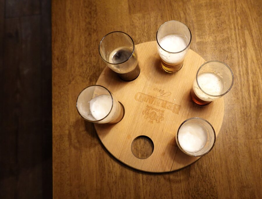 Overhead shot of five craft beer glasses with foam on a round wooden tasting tray