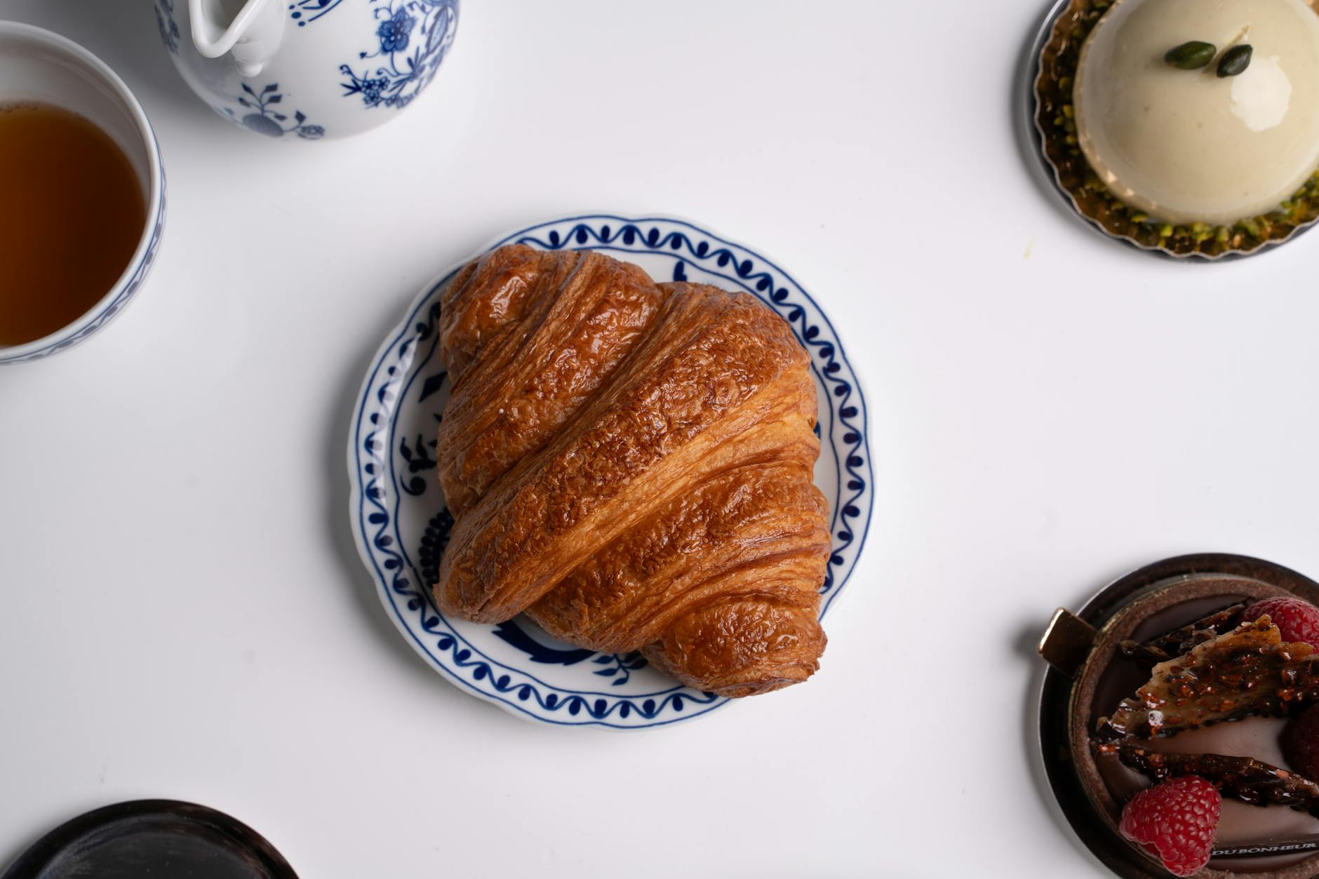 Freshly baked croissant on a decorative plate with coffee for a classic French breakfast