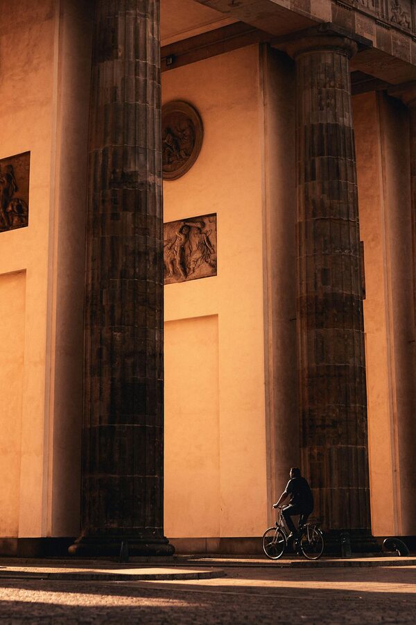 Cyclist riding past Brandenburg Gate in late afternoon