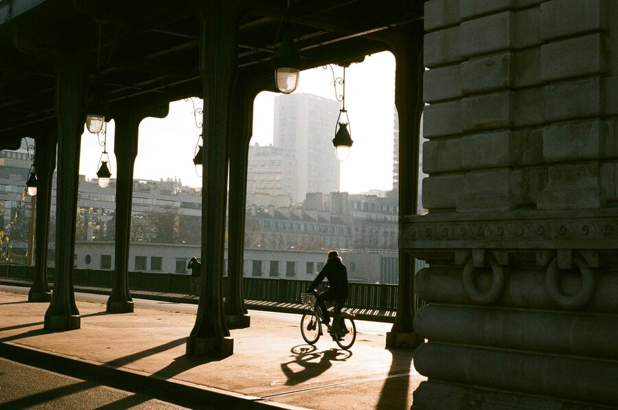 Cyclist crossing an iron bridge in Paris at sunrise