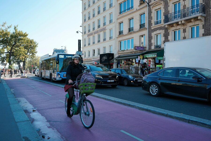Cyclist navigating a busy Paris street with buses