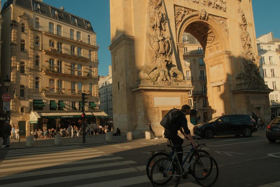 Cyclist at Porte Saint-Denis in Paris at sunset