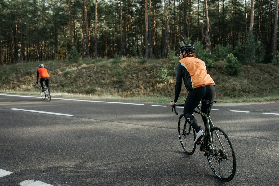 Two cyclists wearing reflective vests on a forest road