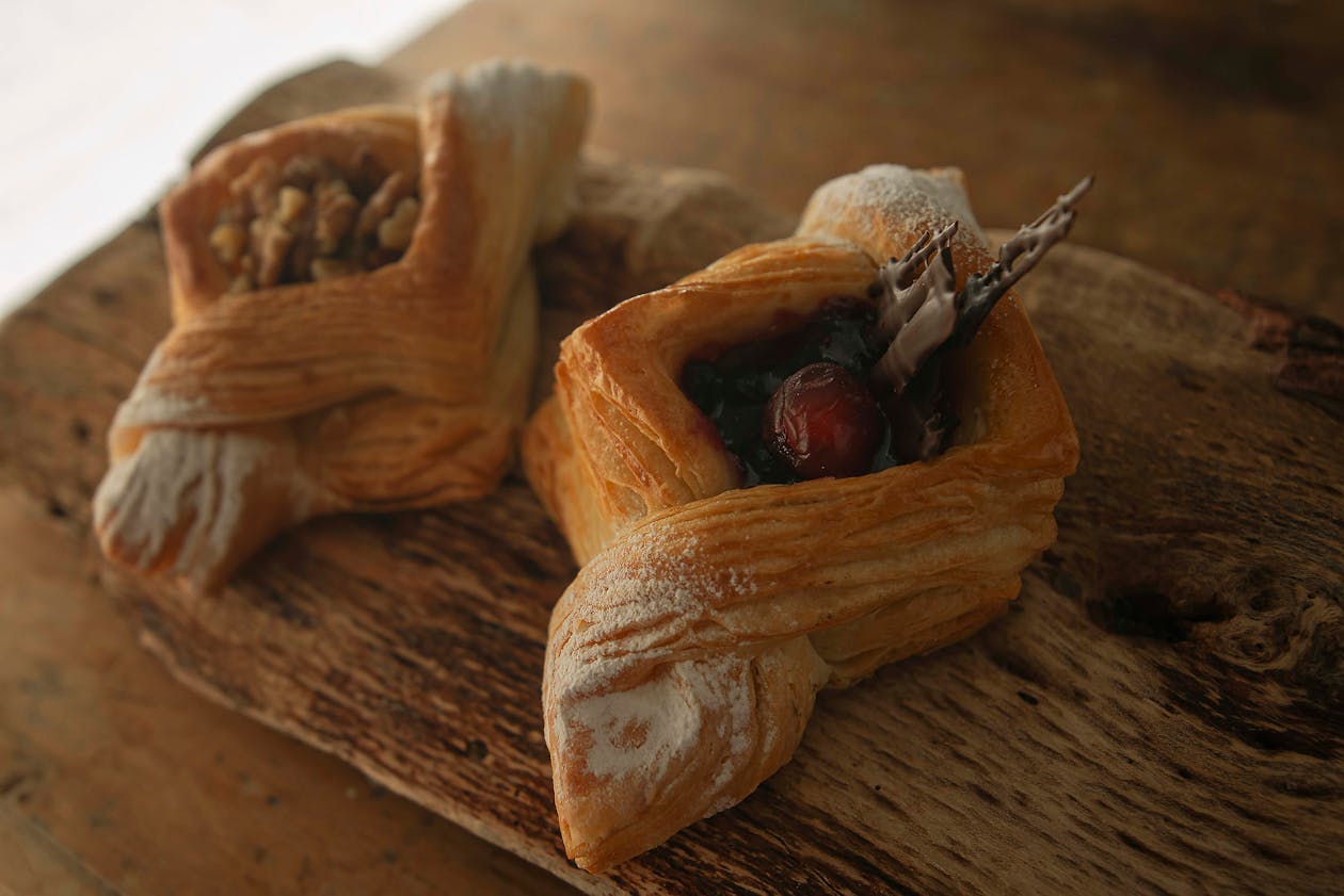 Close-up of artisan Danish pastries topped with fresh fruit and nuts on a wooden board
