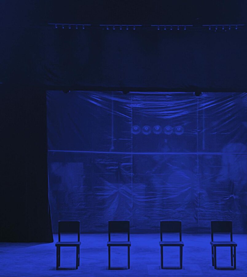 Dark stage with chairs under low blue lighting