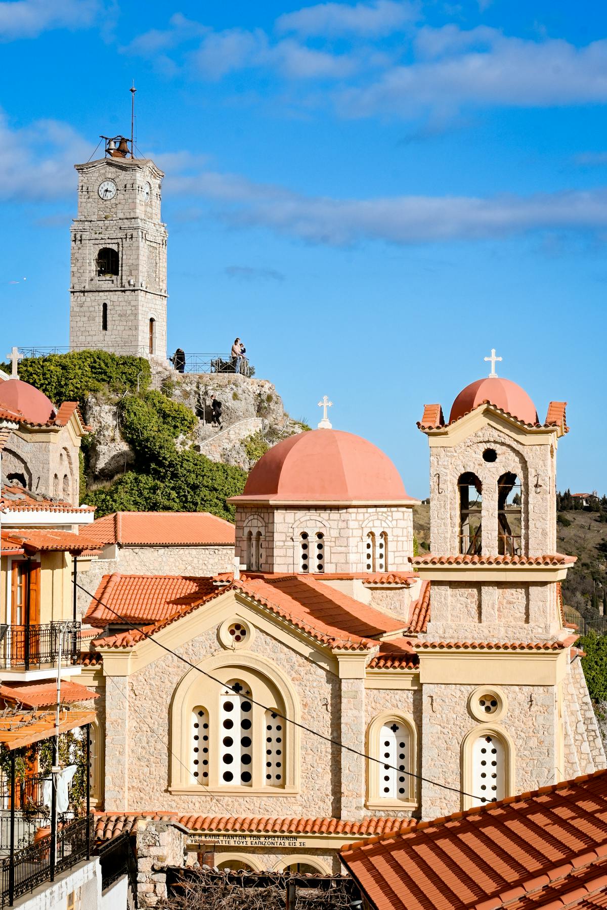 Traditional Greek church and clock tower in Arachova under blue sky