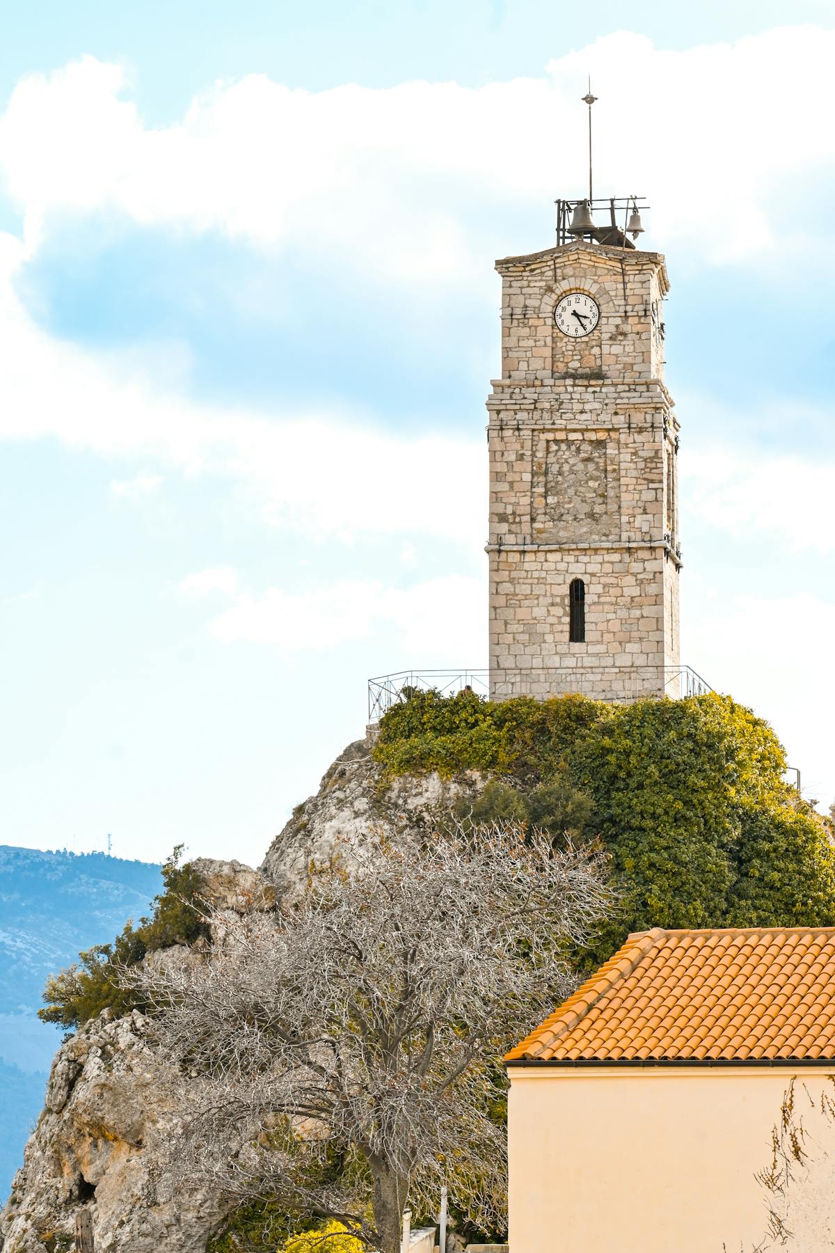 Stone clock tower in Arachova nestled on a hill under blue skies