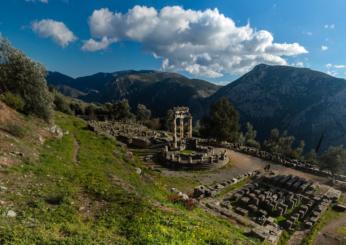 Ancient ruins of Delphi set against a mountain landscape under blue sky