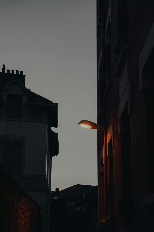 A dimly lit urban street scene at dusk with a glowing street lamp