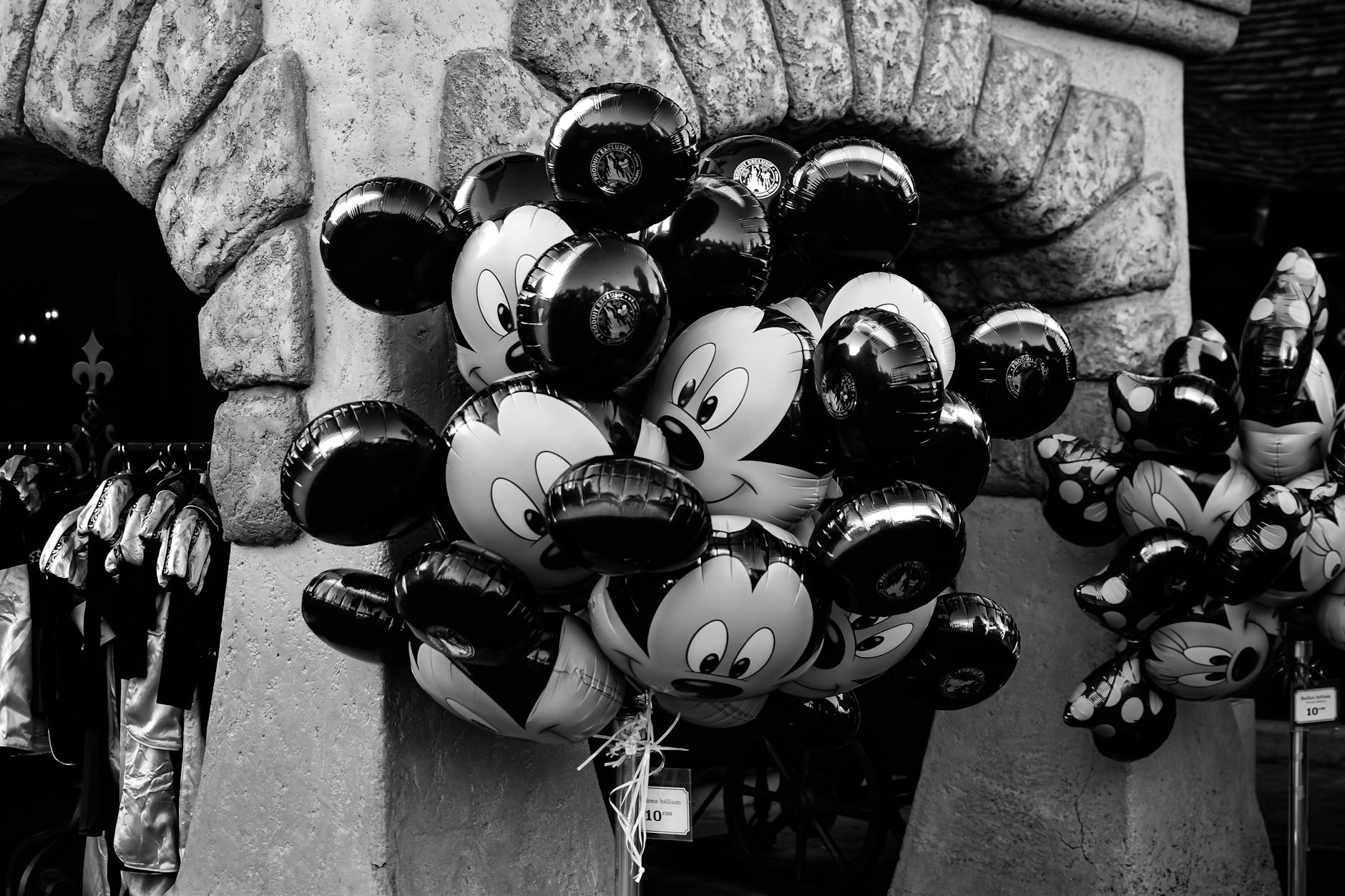 Mickey Mouse themed balloons near a Paris stone arch