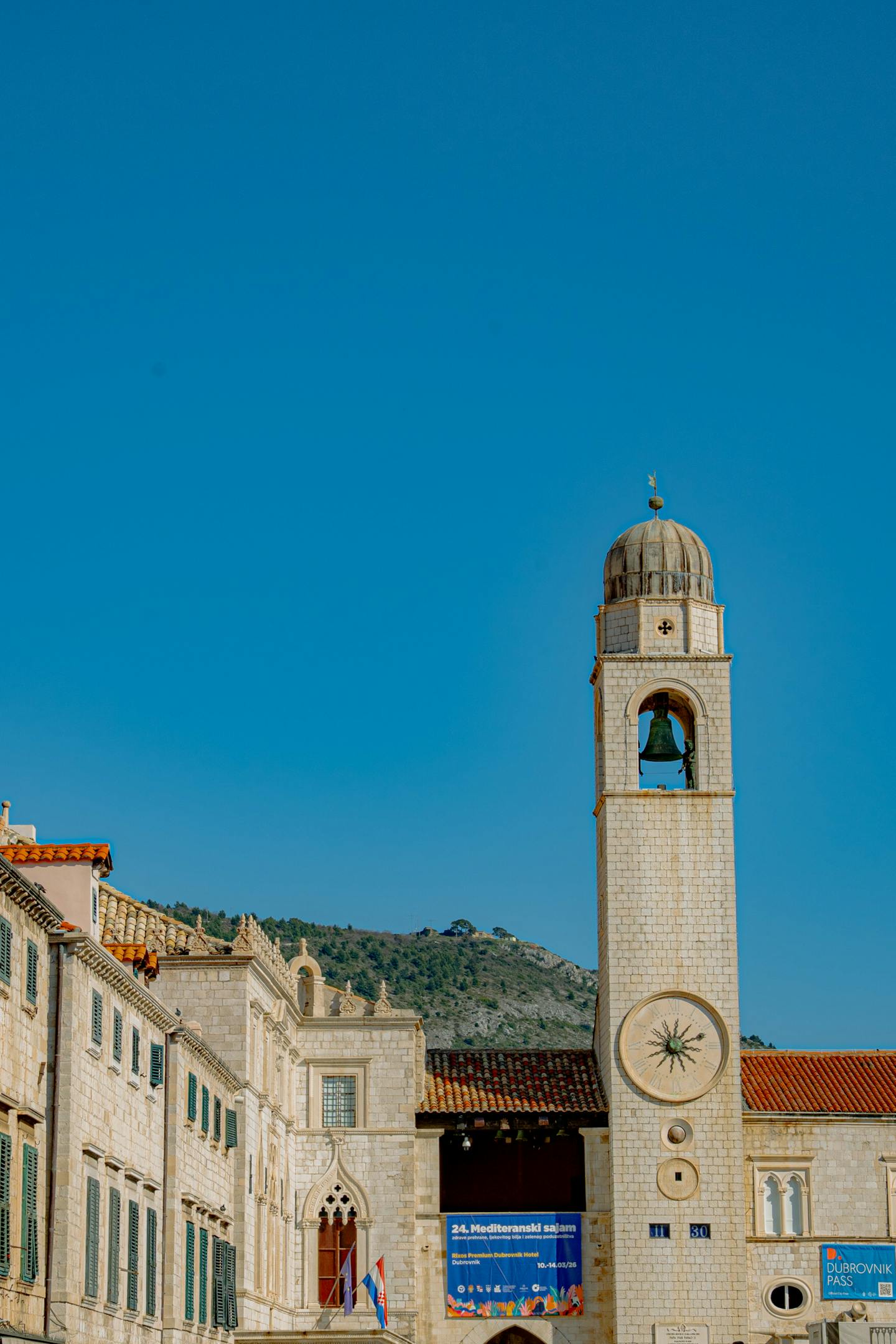 View of Dubrovnik's iconic bell tower rising above the old city under a clear blue sky