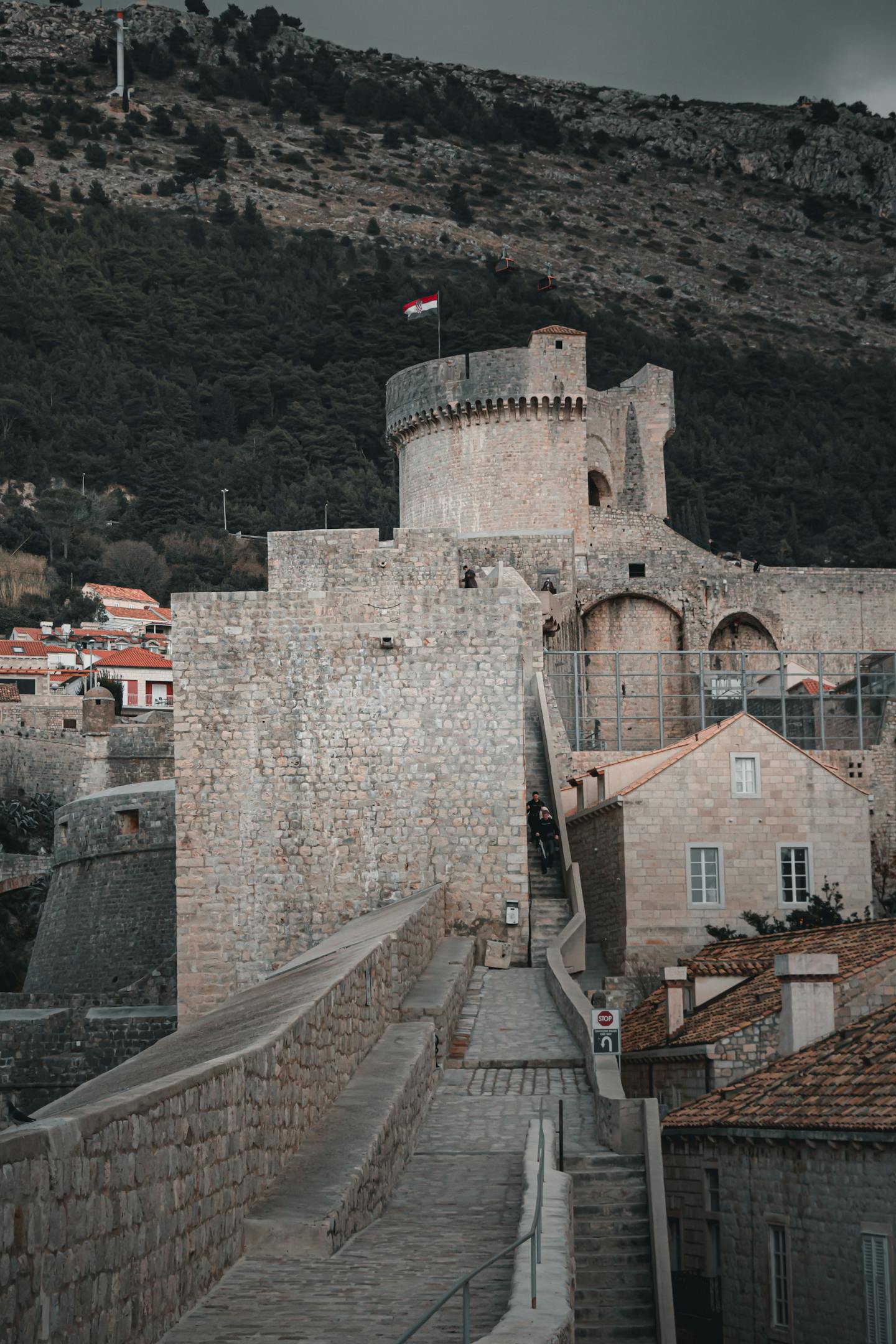 Historic stone fortress with a tower and Croatian flag flying in Dubrovnik
