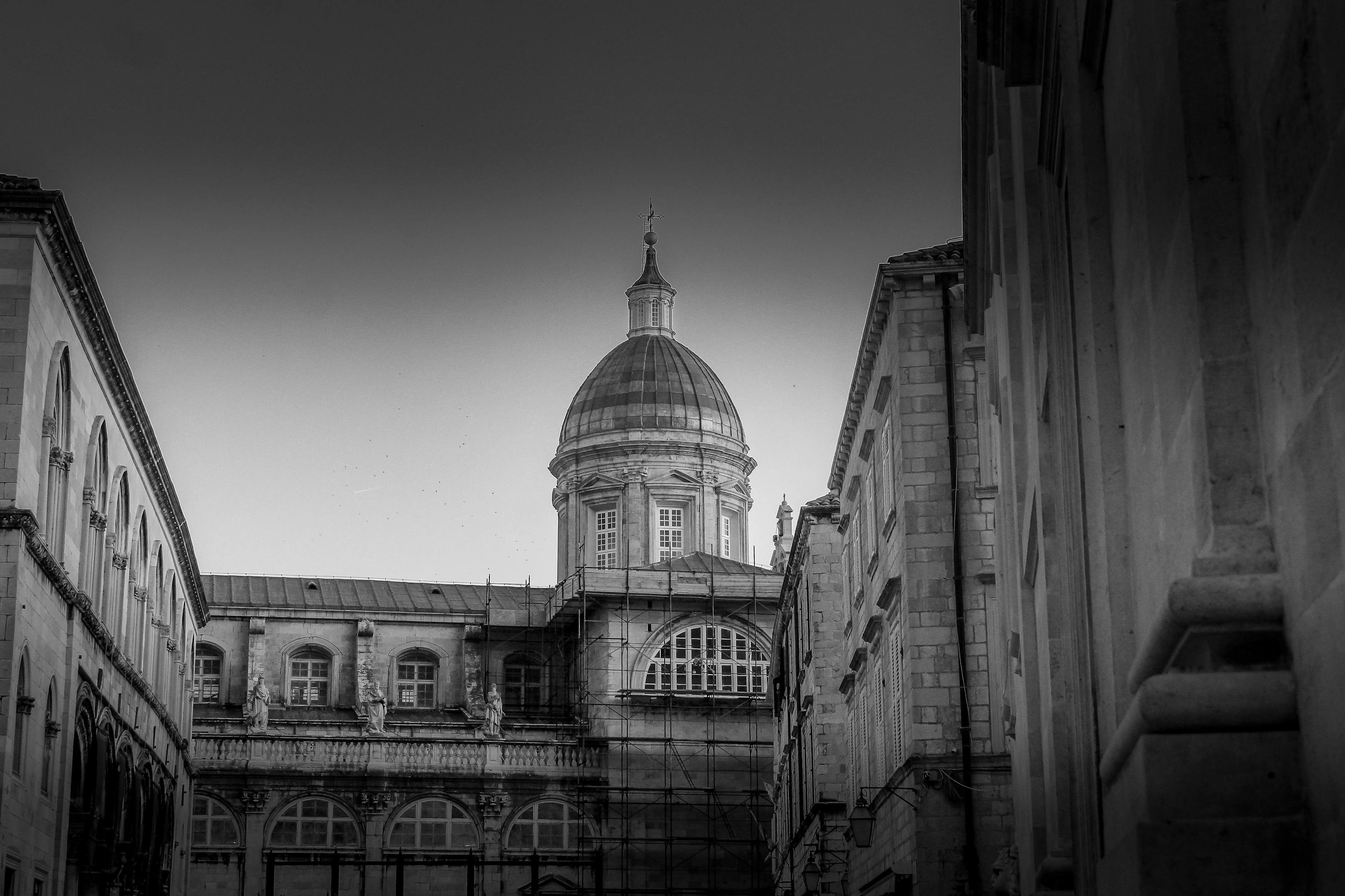 A dramatic black and white photograph of a historic dome in Dubrovnik, Croatia, capturing architectural beauty