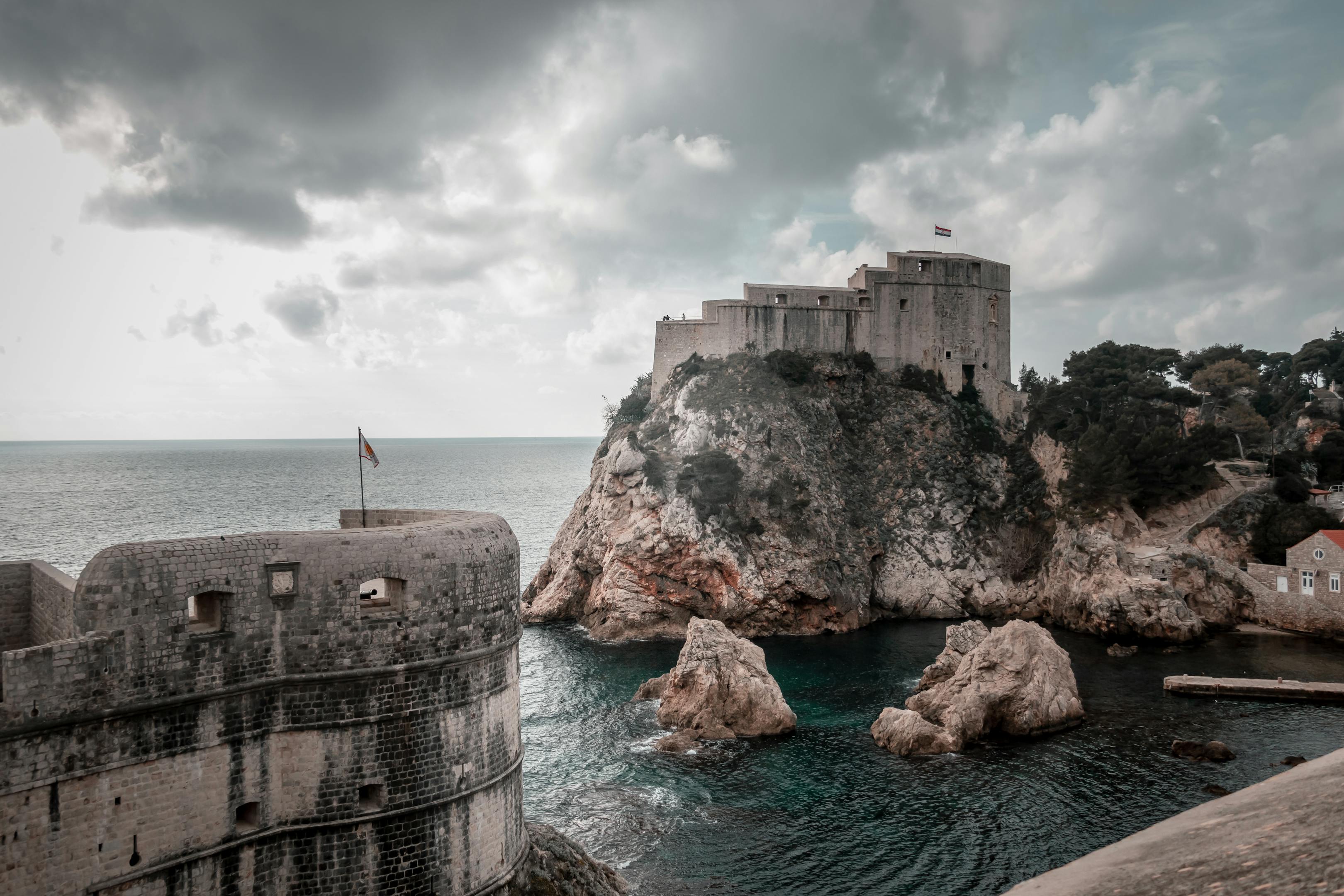Majestic view of Dubrovnik's medieval forts and rocky coast under dramatic skies