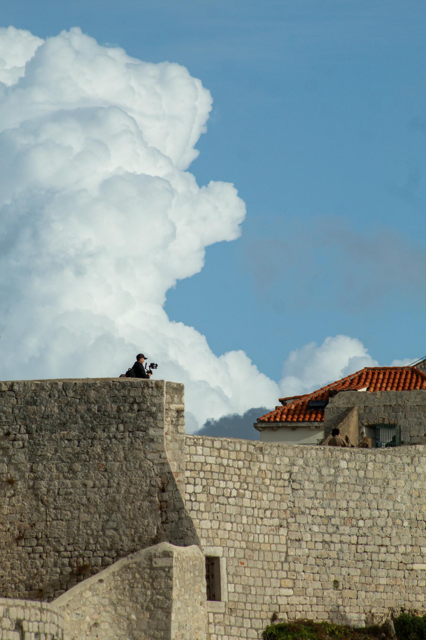 A photographer captures stunning views from Dubrovnik's ancient stone walls under a vivid blue sky