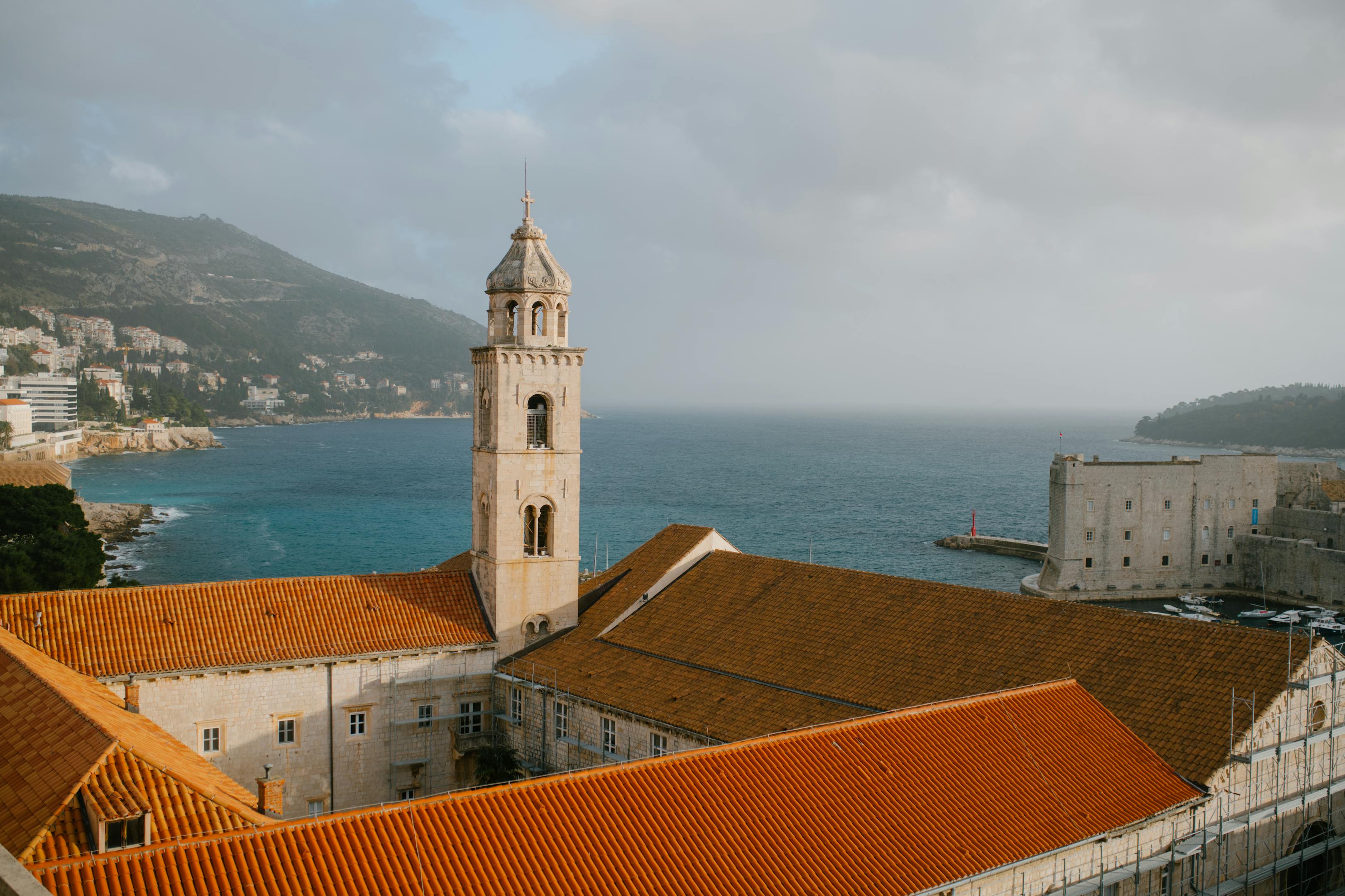 Stone tower with dome on a historic building near the embankment of calm sea in Dubrovnik