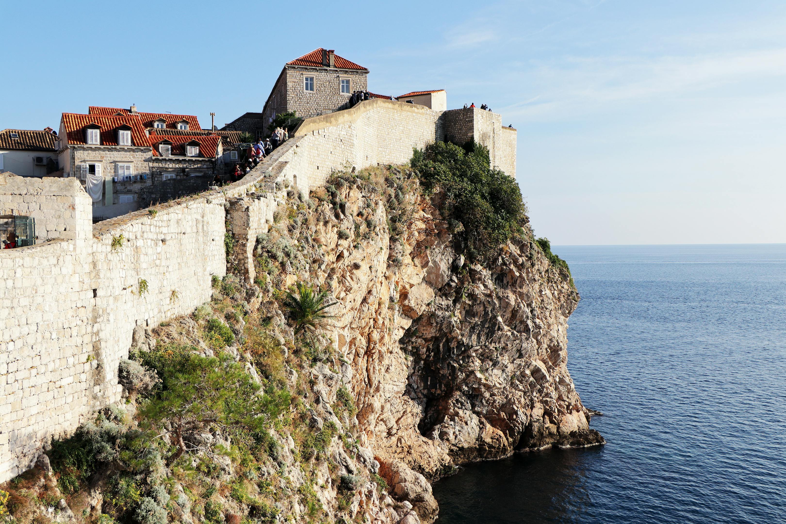 Scenic view of Dubrovnik's ancient fortress walls by the Adriatic Sea on a sunny day