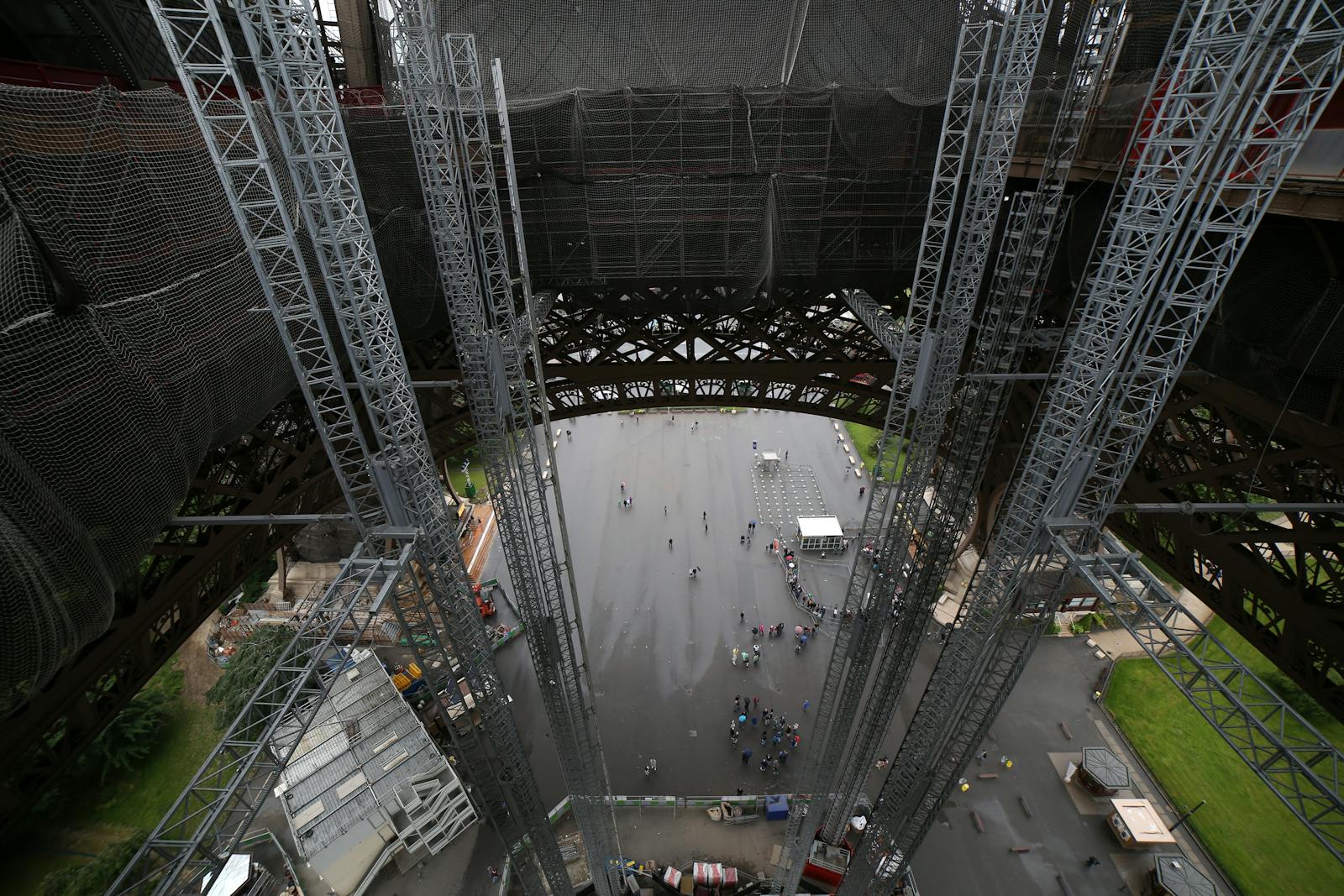 Aerial view from inside the Eiffel Tower showing the iconic ironwork and visitors below