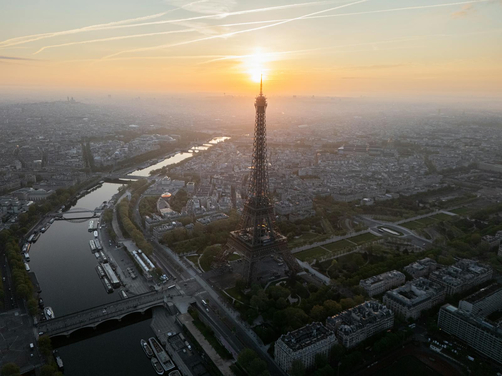Aerial view of the Eiffel Tower at sunrise with the Paris skyline unfolding behind