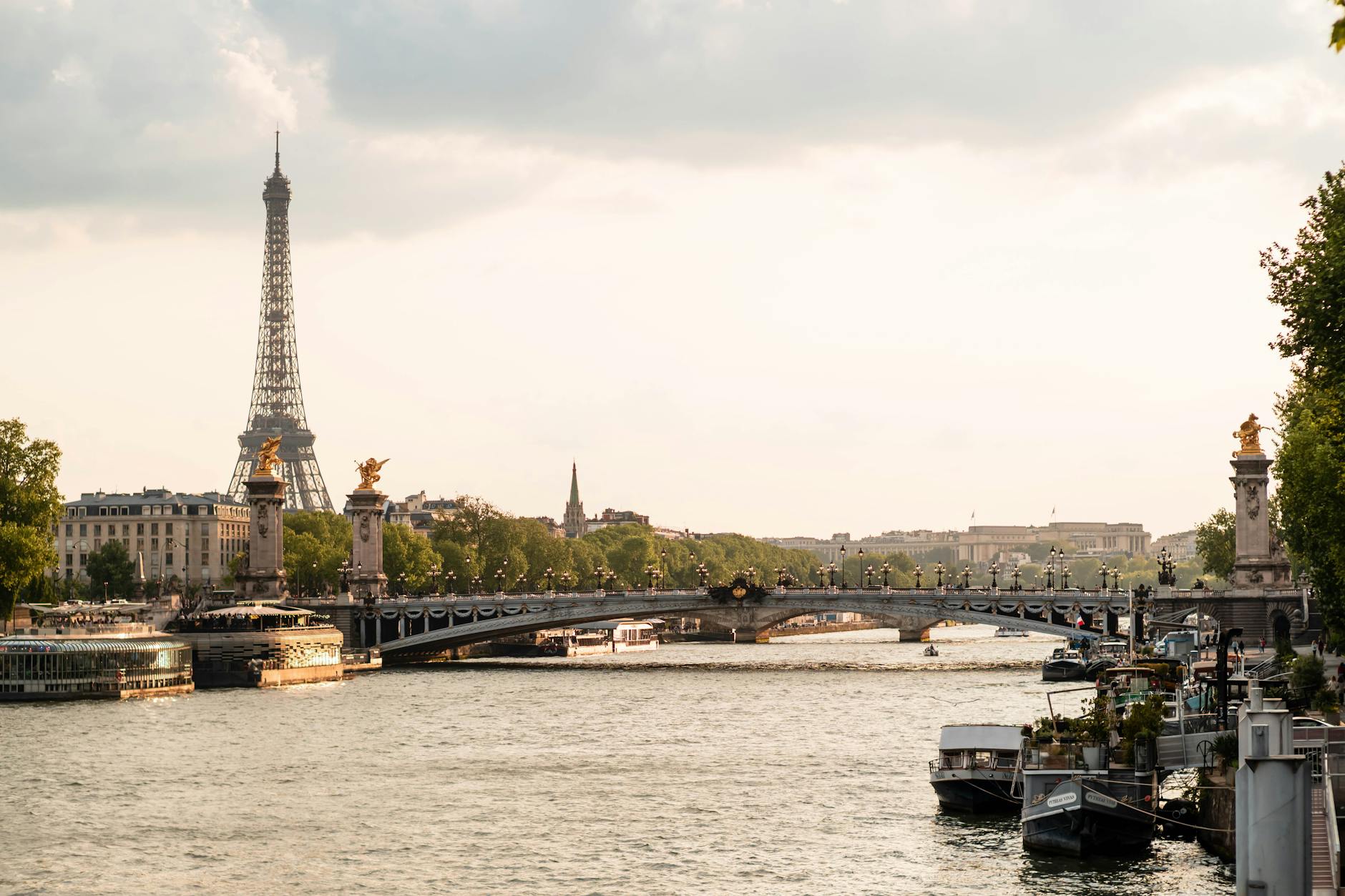 The Eiffel Tower framed by a decorative bridge over the Seine river in Paris