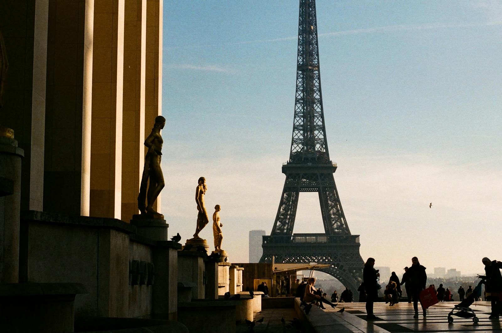 Golden hour view of the Eiffel Tower from the Trocadéro with sculptures in the foreground