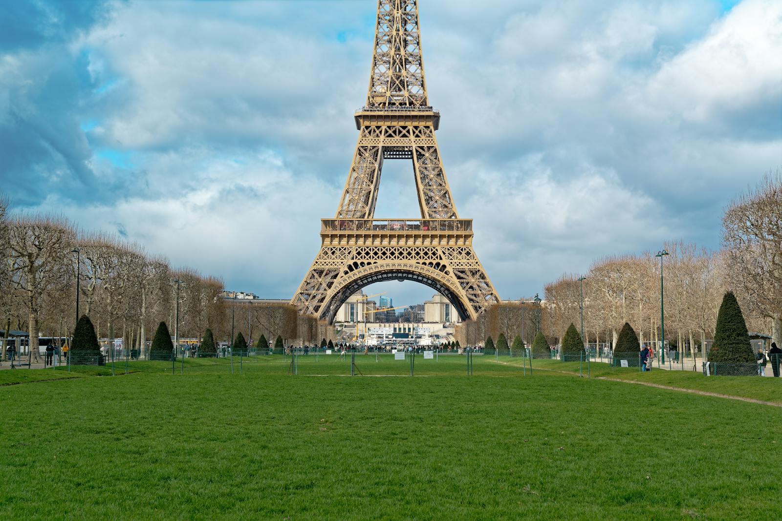 The Eiffel Tower rising above the green lawns of the Champ de Mars on a sunny day