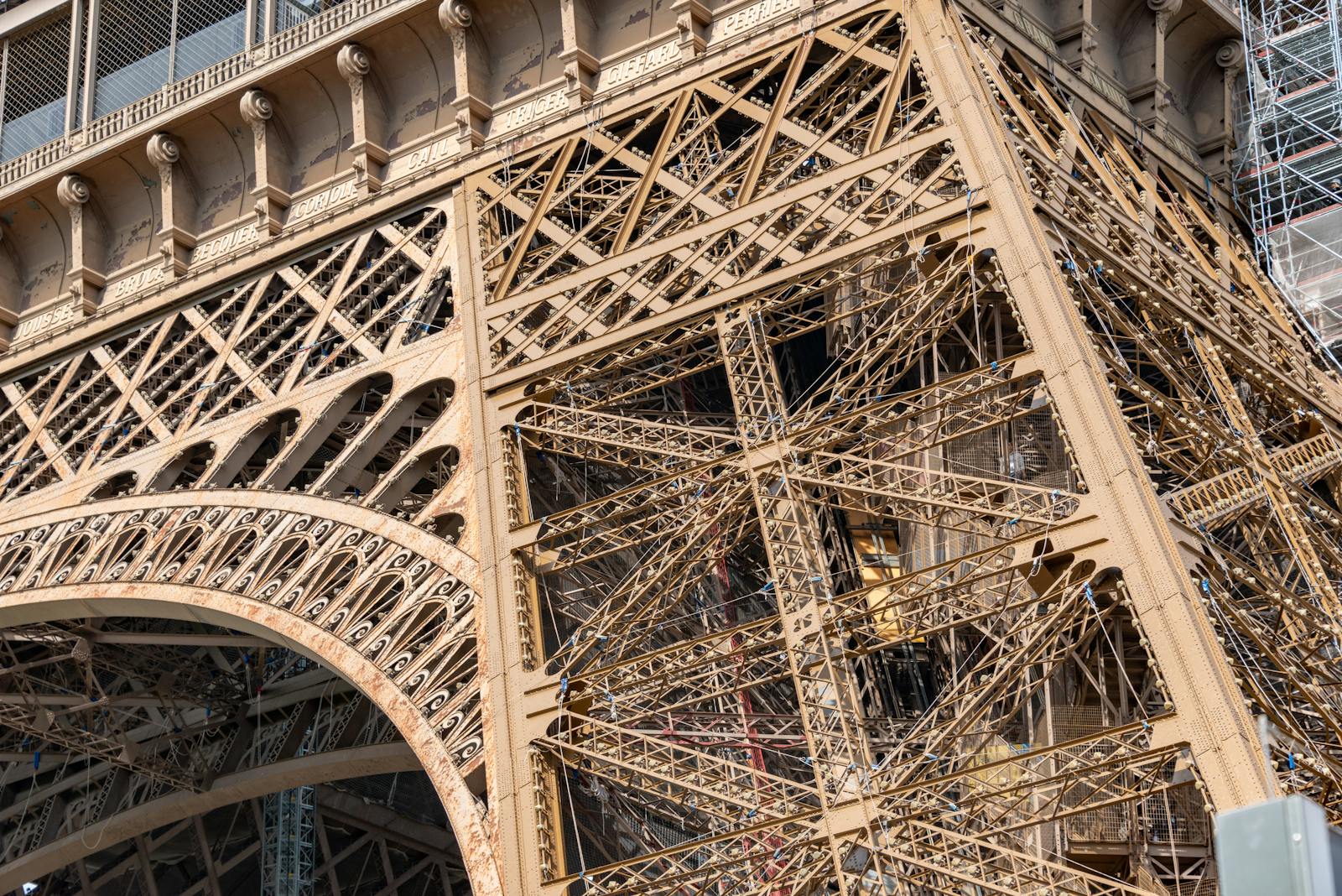 Detailed view of the Eiffel Tower's intricate iron lattice work against the Paris sky