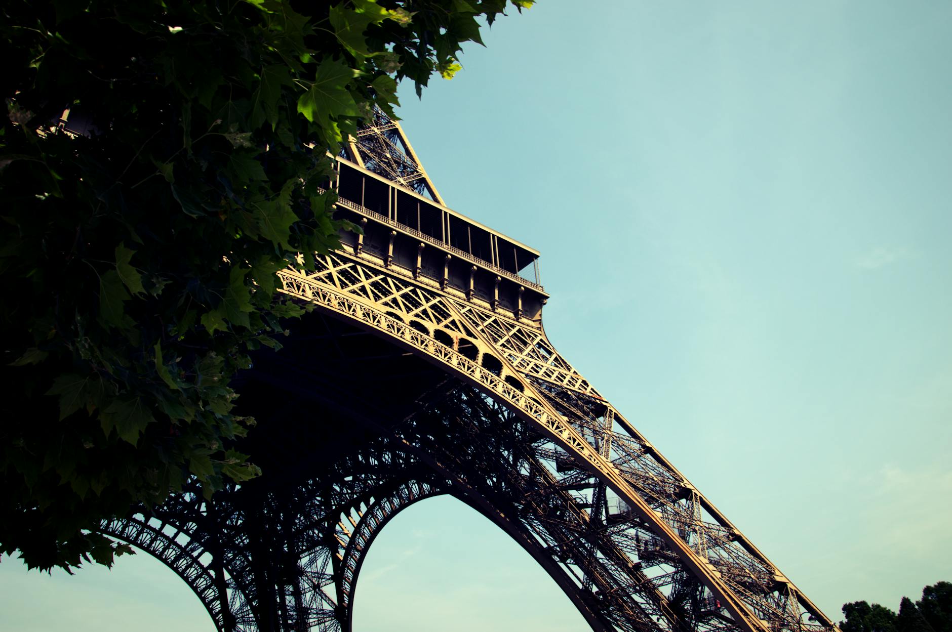Eiffel Tower shot from directly underneath looking up at the iron lattice against blue sky