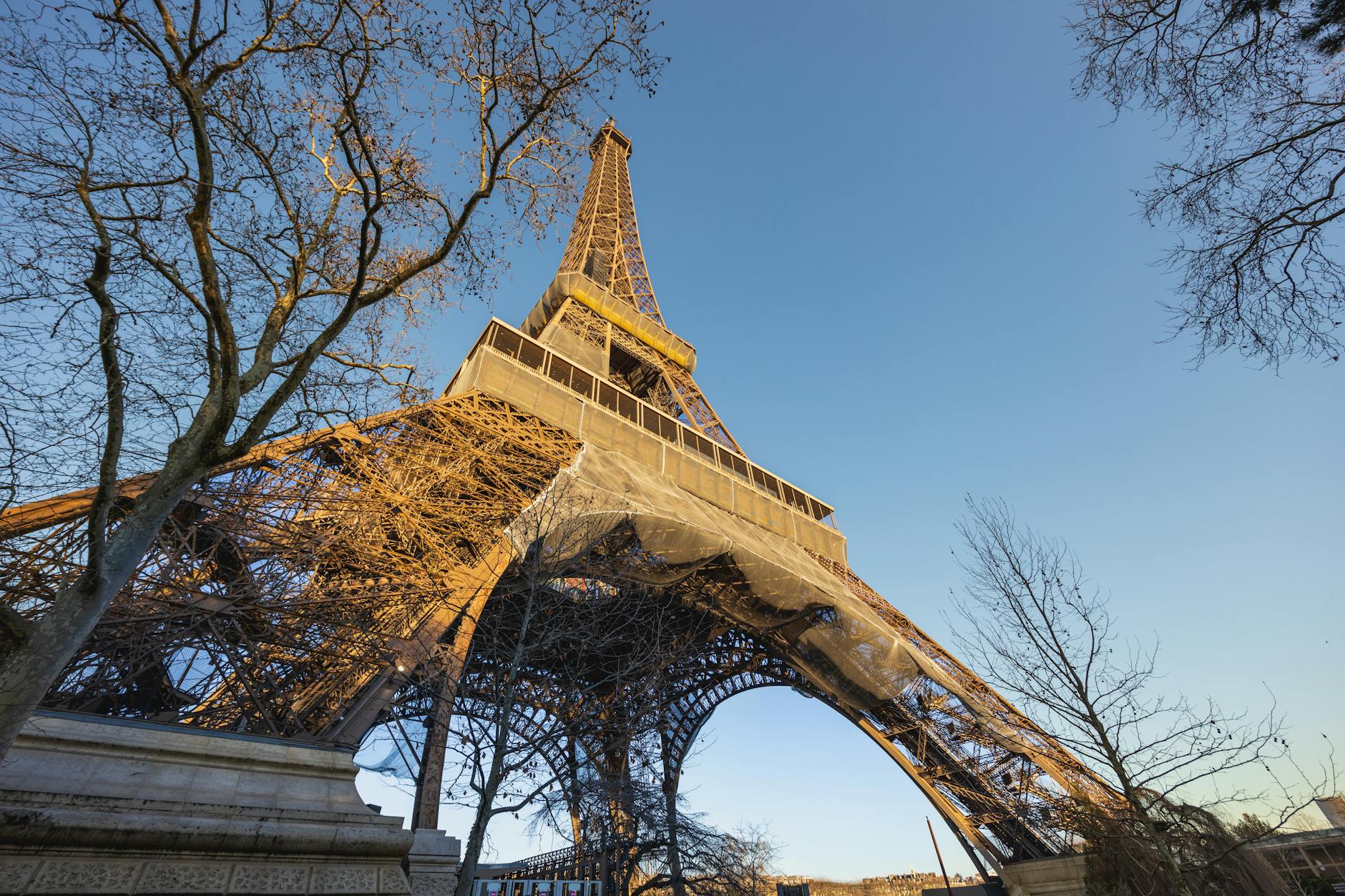 Eiffel Tower at golden hour with sun flaring through the iron lattice
