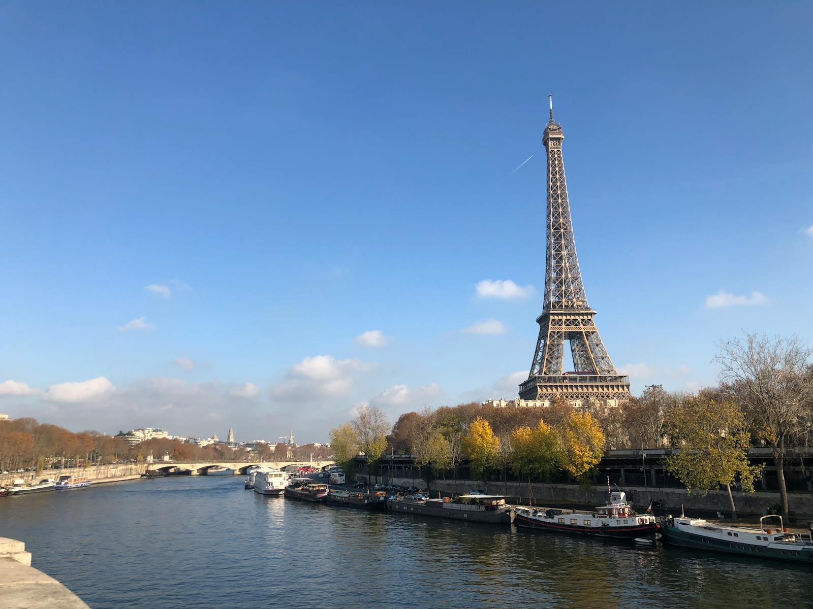Eiffel Tower viewed from the Seine with cruise boats passing on a clear day