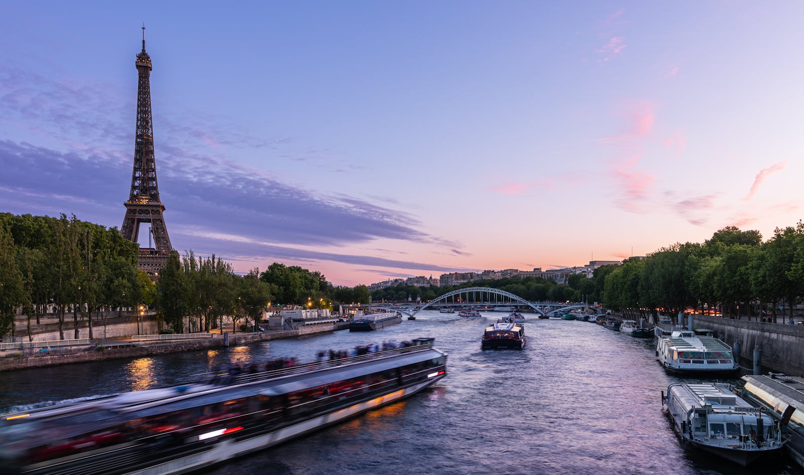 Eiffel Tower at twilight with cruise boats on the Seine River