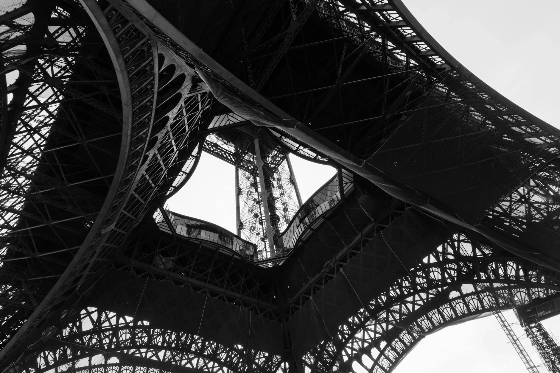 Black and white photograph of the Eiffel Tower from directly underneath the central arch