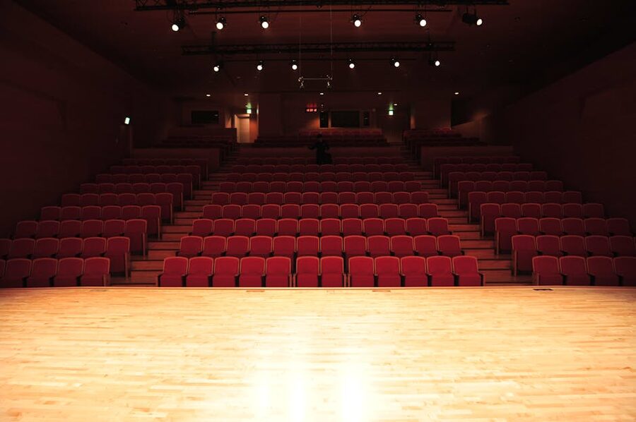 Empty theater with red seats and illuminated stage