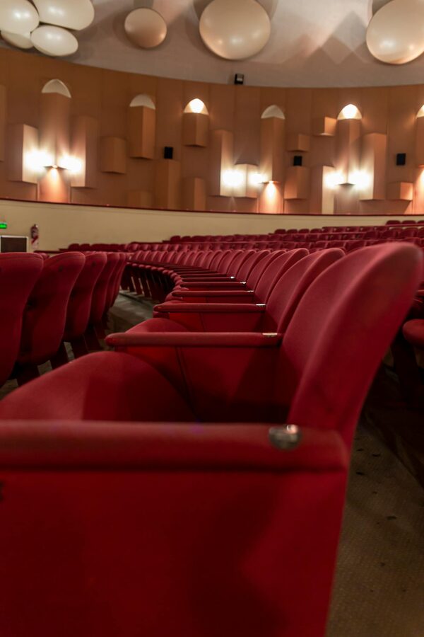 Empty theater with red seats highlighting architectural details