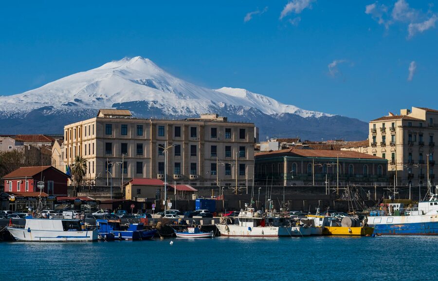 Mount Etna snowy peaks over Catania harbor Sicily