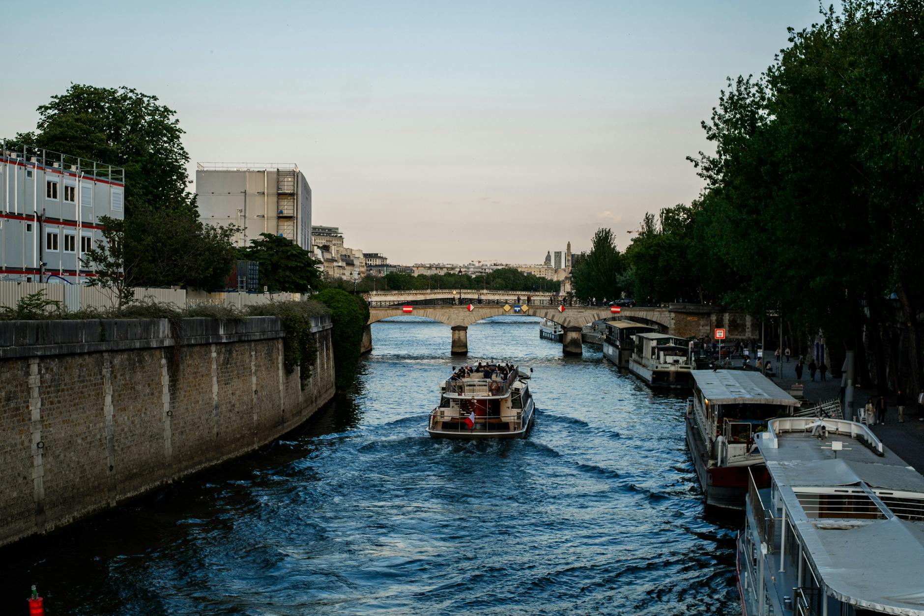 An evening boat cruising under a Paris stone bridge on the Seine