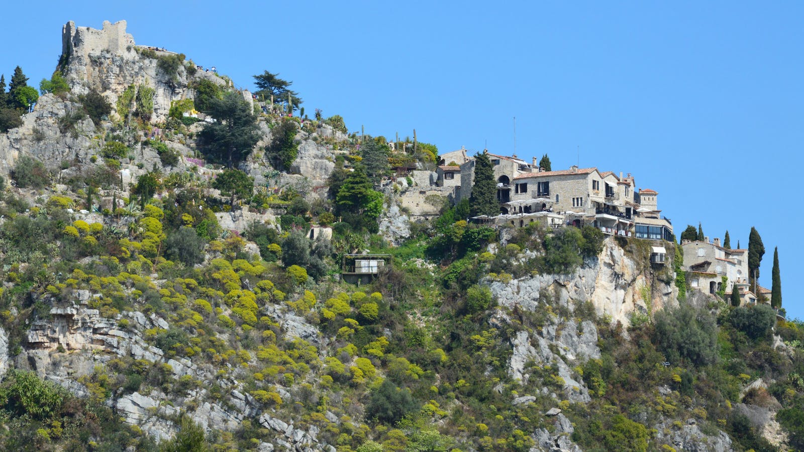 Stone houses of Eze village perched on a rocky hill under a clear blue sky