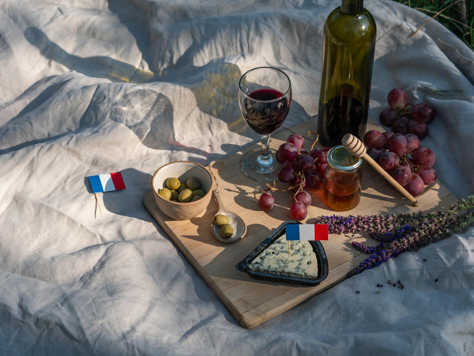 Outdoor French meal with wine, cheese and olives set on a wooden table