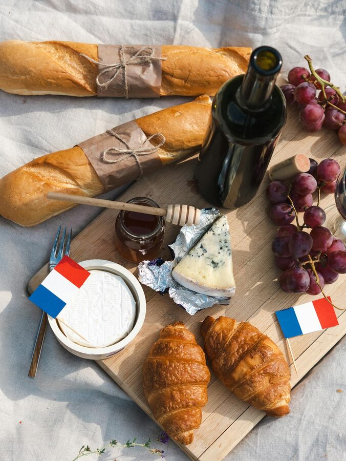 French picnic spread with baguettes cheese wine grapes and croissants