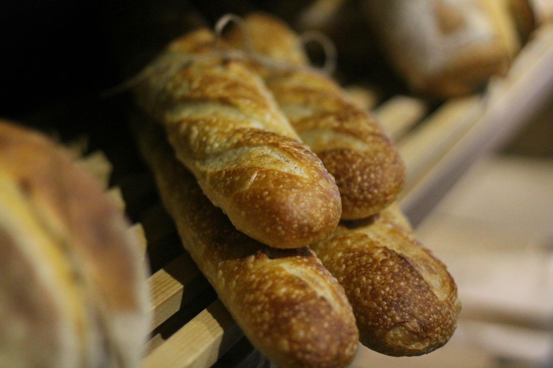 Fresh French baguettes stacked on a wooden shelf at a Paris boulangerie