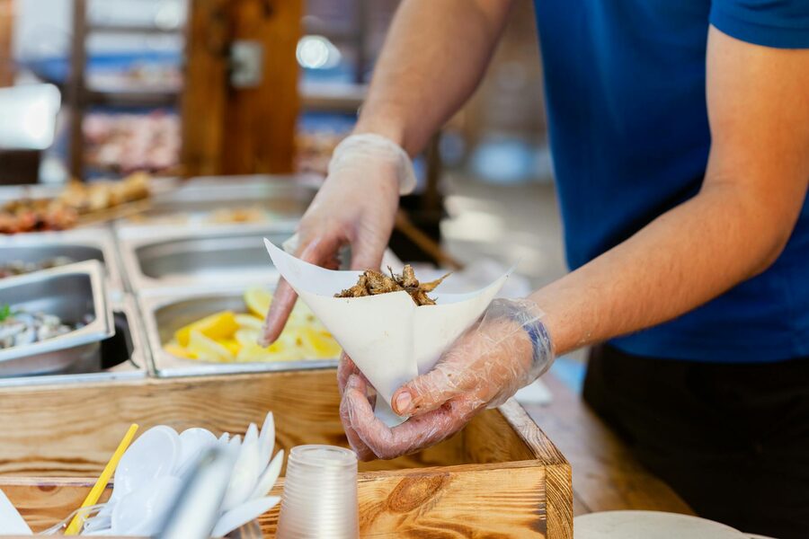 Vendor serving fried food in paper cone at street market