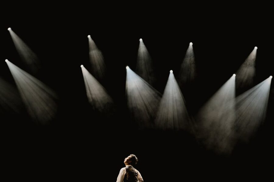 Solo performer in spotlight on dark stage