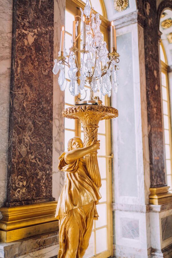 Golden sculpture holding chandelier in an ornate palace