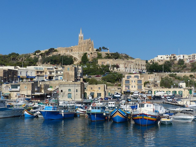 Mgarr harbour Gozo with traditional boats and hilltop church