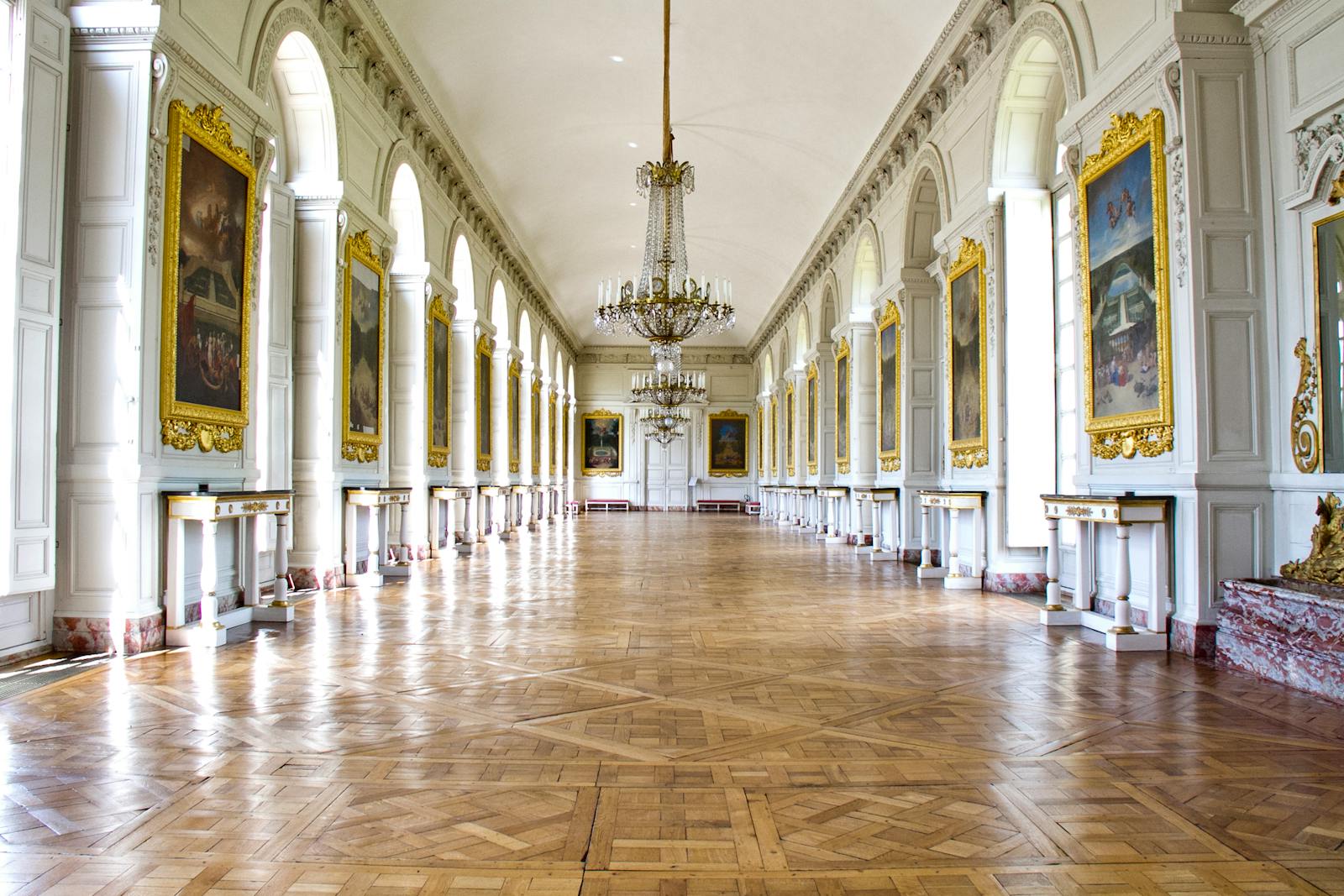 Luxurious hallway inside the Grand Trianon at Versailles with ornate chandeliers