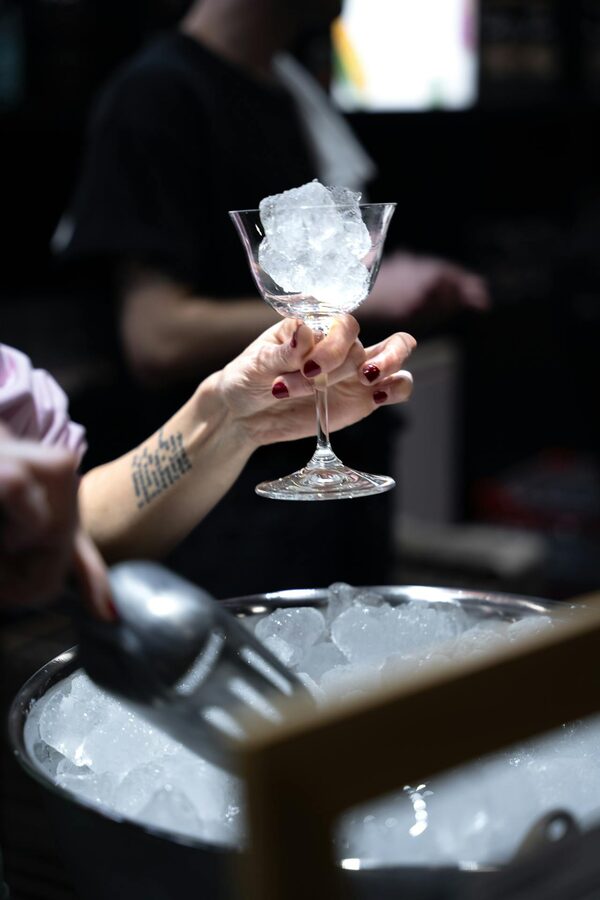 Hand holding cocktail glass with ice in a Paris bar