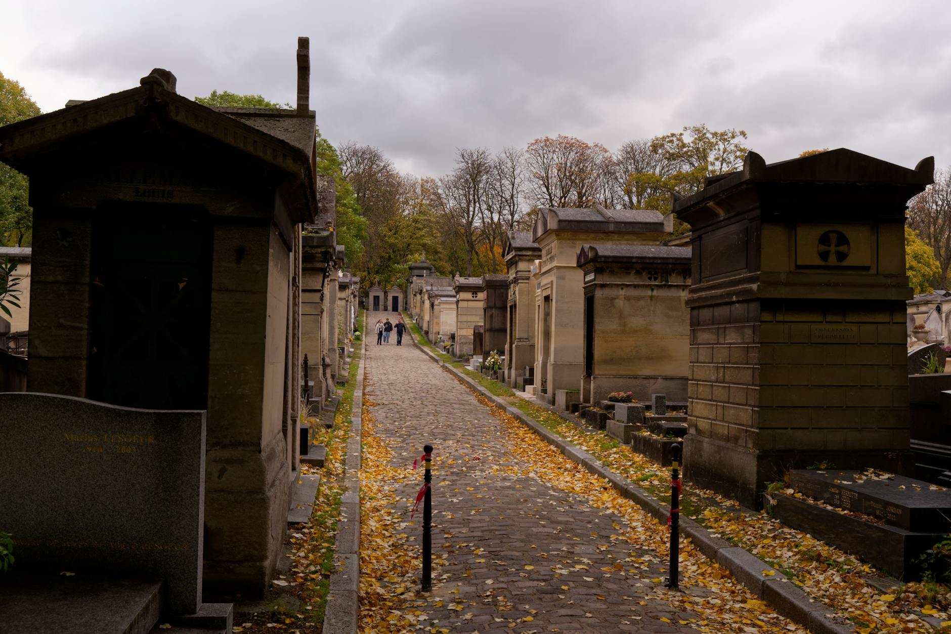 Historic cemetery path lined with tombs on an autumn day
