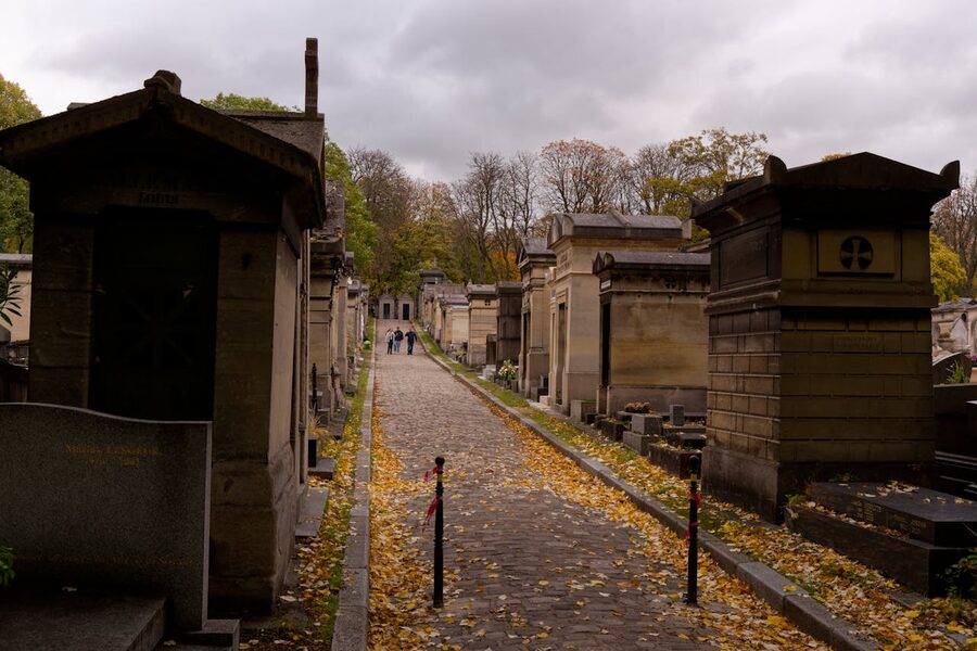 Historic cemetery path lined with tombs on an overcast autumn day