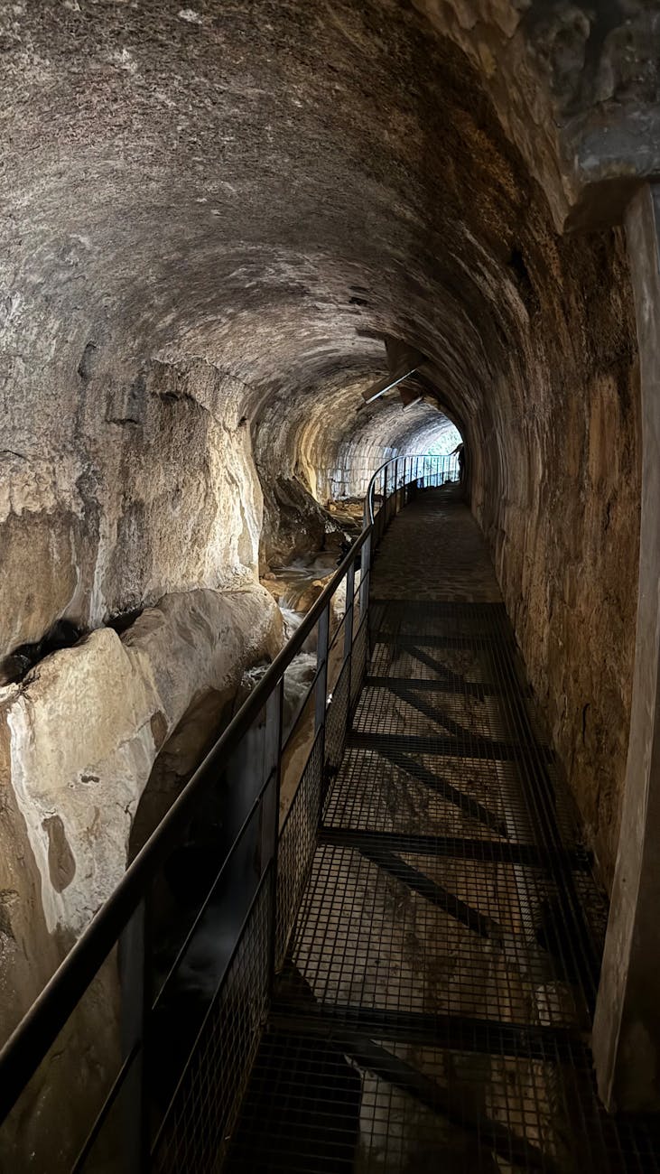 Historic underground tunnel with stone walls and metal walkway